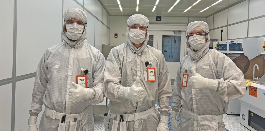 A photo of three people dressed in PPE with their thumbs up.